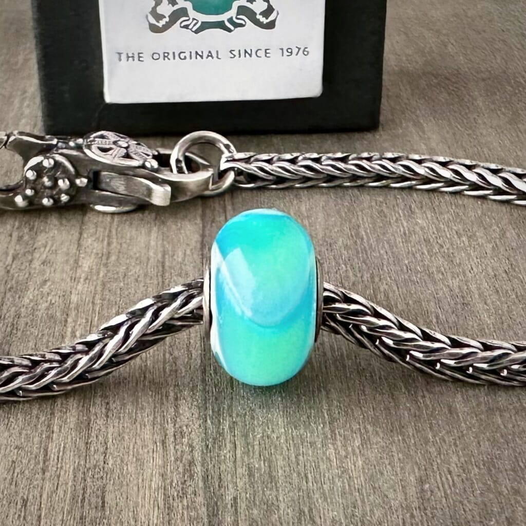 Available at Suzie Q Studio dot com, Trollbeads retired TURQUOISE ARMADILLO, glass bead, in a tropical, swimming-pool-blue, shown on a silver chain with a clasp.