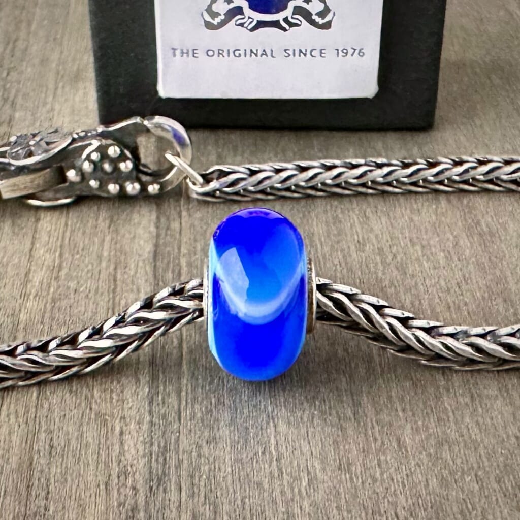 Available at Suzie Q Studio dot com, Trollbeads retired BLUE ARMADILLO glass bead, shown on a silver chain with a clasp.