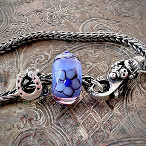 Suzie Q Studio's beautiful limited edition Trollbeads "GOOD LUCK" Starter Bracelet includes: a sterling silver "messenger of good luck" bead, a gorgeous glass bead with the flower of Love, and a ladybug lock as well as a Trollbeads classic foxtail-chain bracelet.