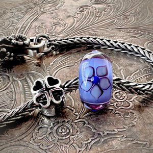 Suzie Q Studio's beautiful limited edition Trollbeads "GOOD LUCK" Starter Bracelet includes: a sterling silver "messenger of good luck" bead, a gorgeous glass bead with the flower of Love, and a ladybug lock as well as a Trollbeads classic foxtail-chain bracelet.