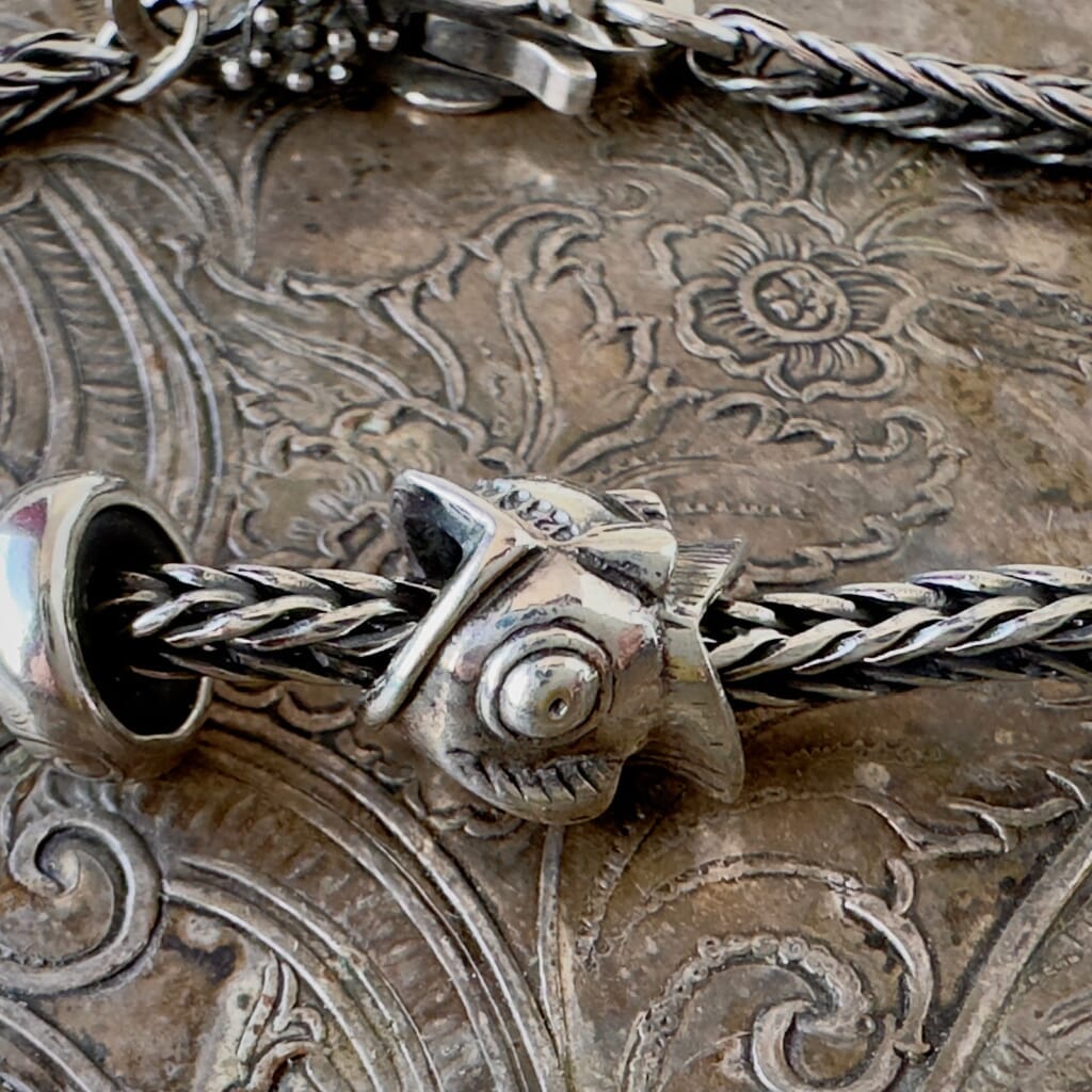 Trollbeads, NEITHER FISH NOR BIRD, BIG is a whimsical, fish-bird design, sterling silver bead, shown on a silver Trollbeads bracelet.