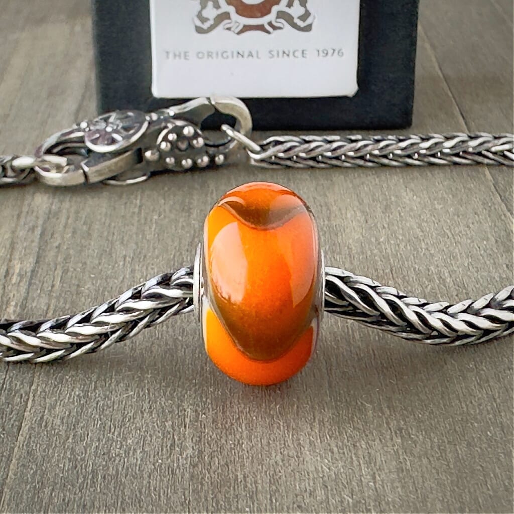 Available at Suzie Q Studio dot com, Trollbeads retired ORANGE ARMADILLO #1, glass bead, shown on a silver chain with a clasp.