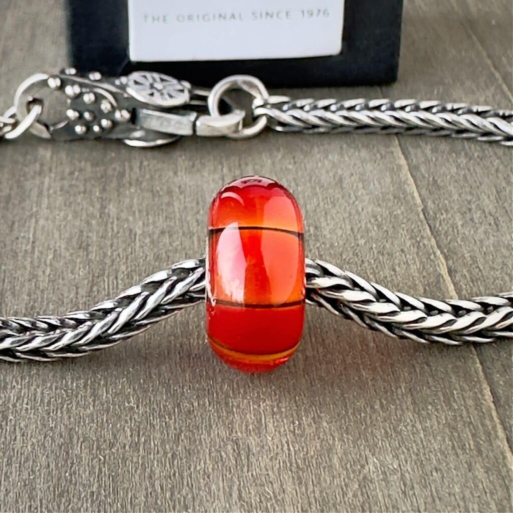 Available at Suzie Q Studio dot com, Trollbeads retired "PUMPKIN" glass bead, in gorgeous, vibrant orange tones, shown on a silver chain with a clasp.