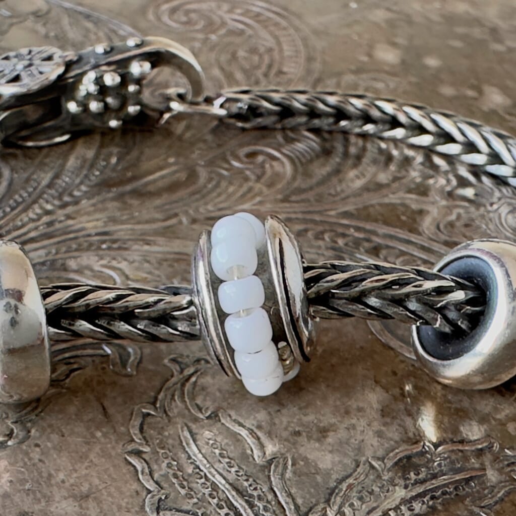 Trollbeads, World Tour, SEED BEAD, features small white glass seed beads around this sterling silver bead, and are used in the world-renowned Ndebele beadwork of South Africa. Visit Suzie Q Studio (suzieqstudio.com) for new stock, never worn, collectible, Rare & Retired Trollbeads.