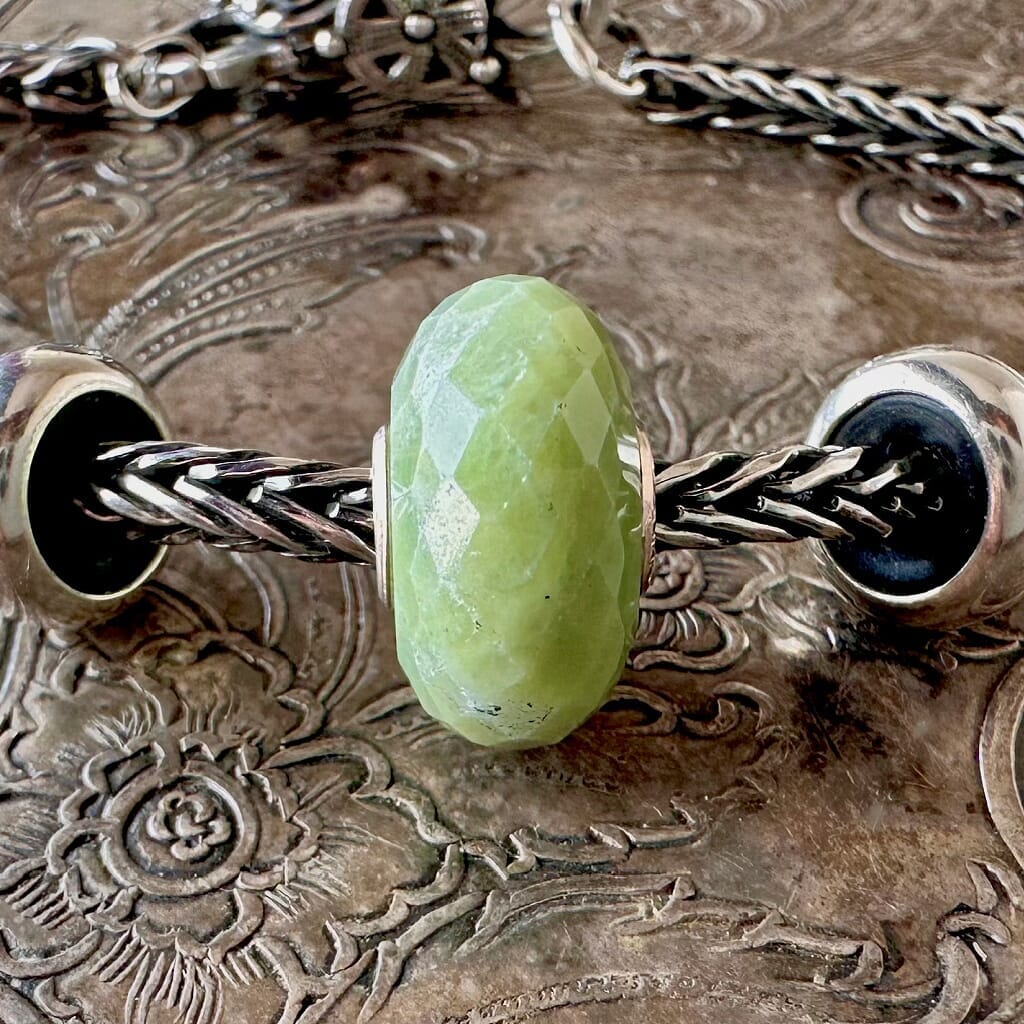 Trollbeads SERPENTINE faceted, gemstone bead is a calming, opaque green colour, and is shown on a Trollbeads silver bracelet.