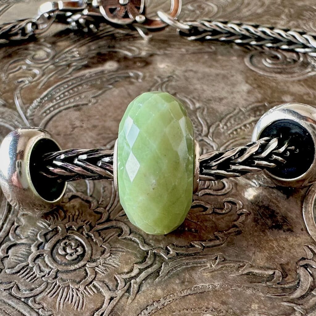 Trollbeads SERPENTINE faceted, gemstone bead is a calming, opaque green colour, and is shown on a Trollbeads silver bracelet.