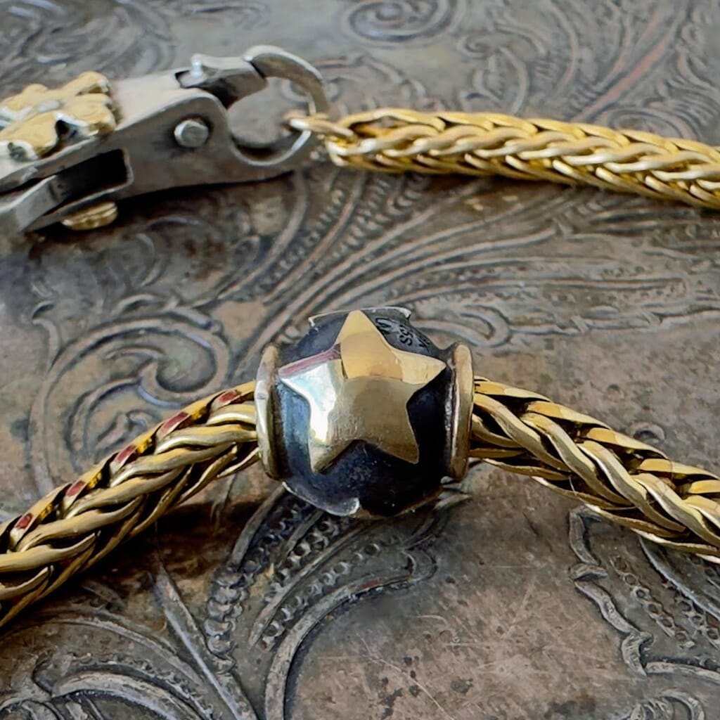 Trollbeads  STARS bead, features 3, 18KT gold stars, floating on a velvety, dark patina, sterling silver bead, and shown on a Trollbeads gold chain.