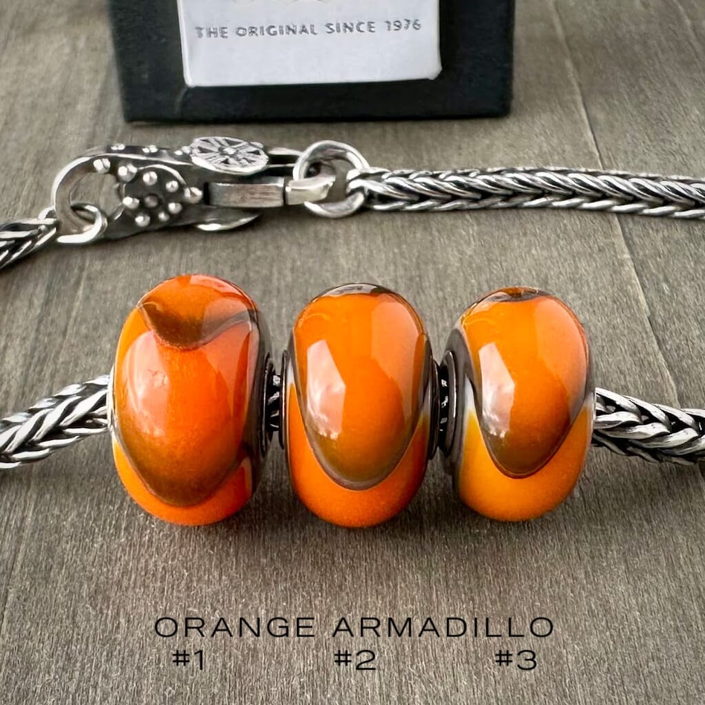 Available at Suzie Q Studio dot com, Trollbeads retired ORANGE ARMADILLO #3, glass bead, shown on a silver chain with a clasp.